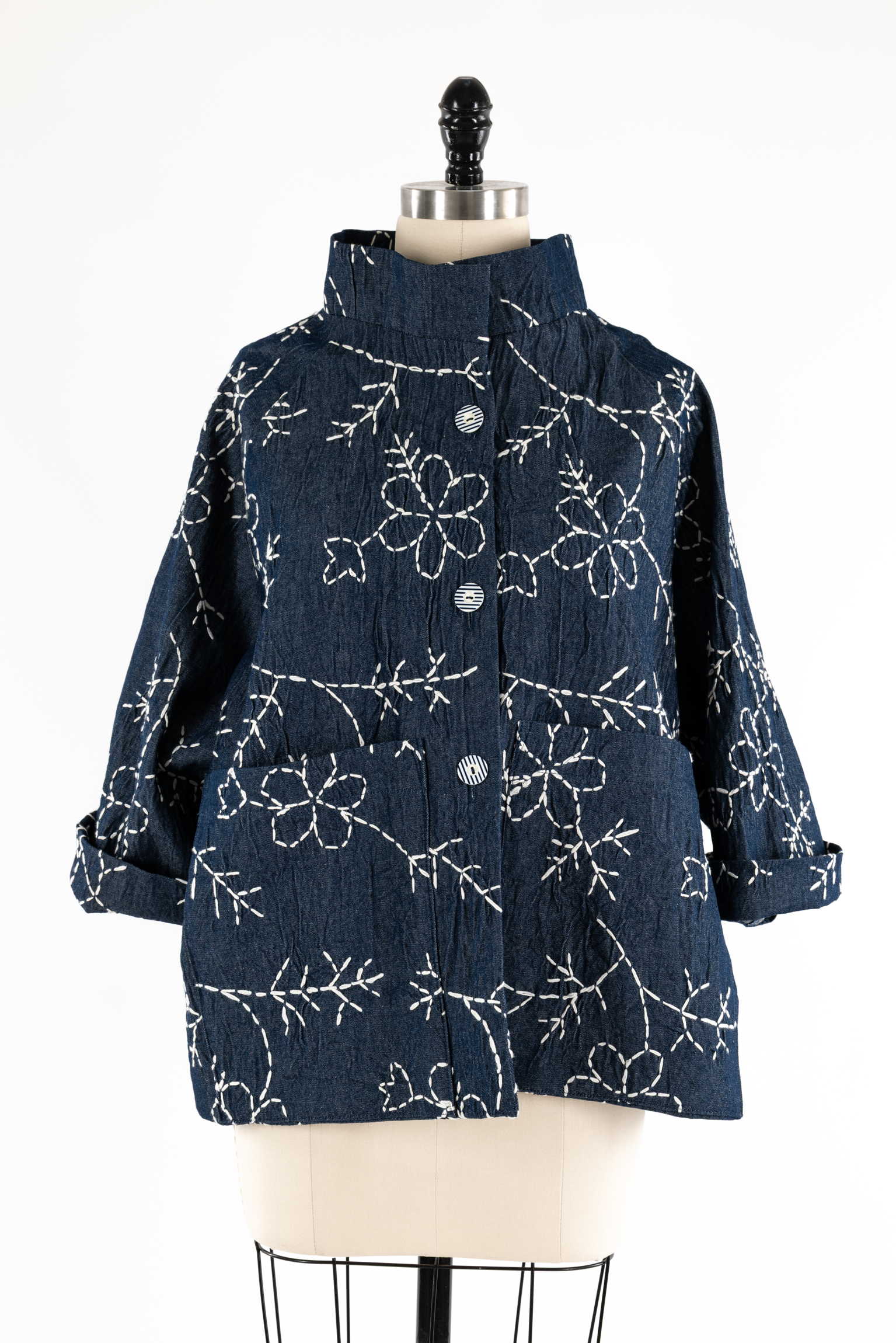 Denim jacket with white floral embroidery, button front, rolled sleeves, displayed on mannequin
