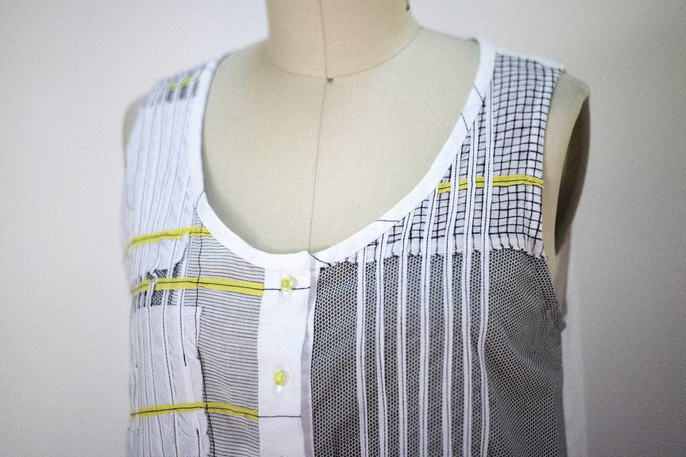 Sleeveless patchwork top with striped, checkered, and mesh panels, yellow accents, and button front