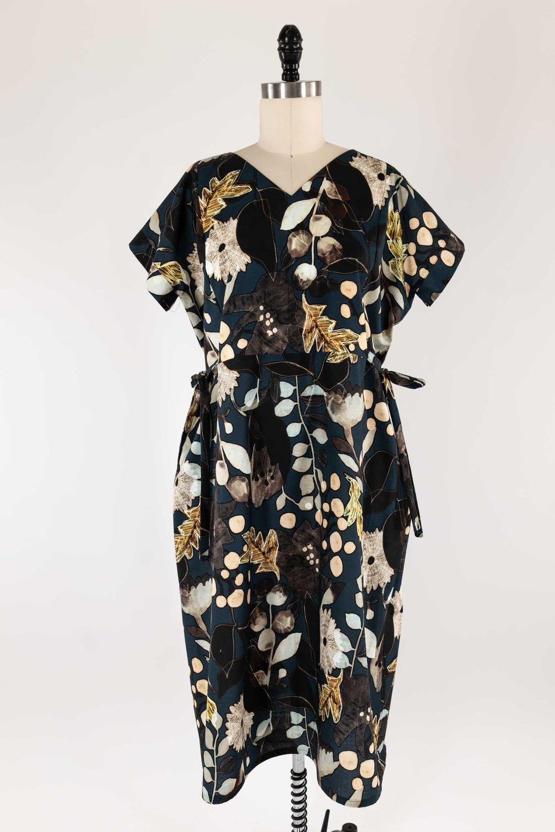 Floral print dress with gold accents on dark fabric, displayed on mannequin for sewing projects
