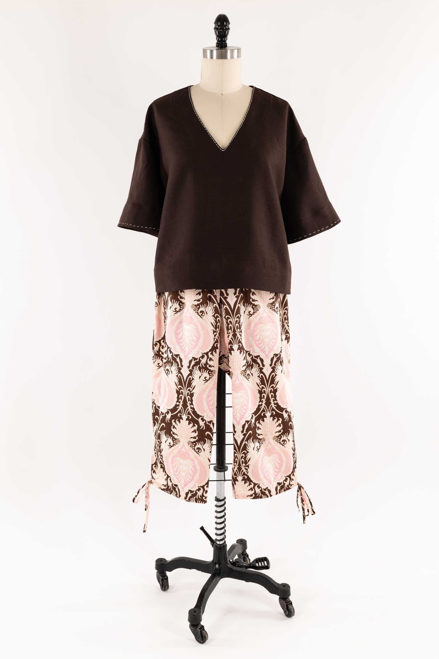 Brown V-neck top with pink and brown damask print pants on mannequin, ideal for sewing projects