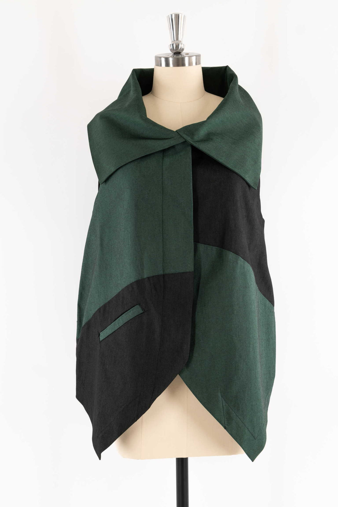 Green and black color-blocked poncho with pocket, styled on mannequin for sewing projects