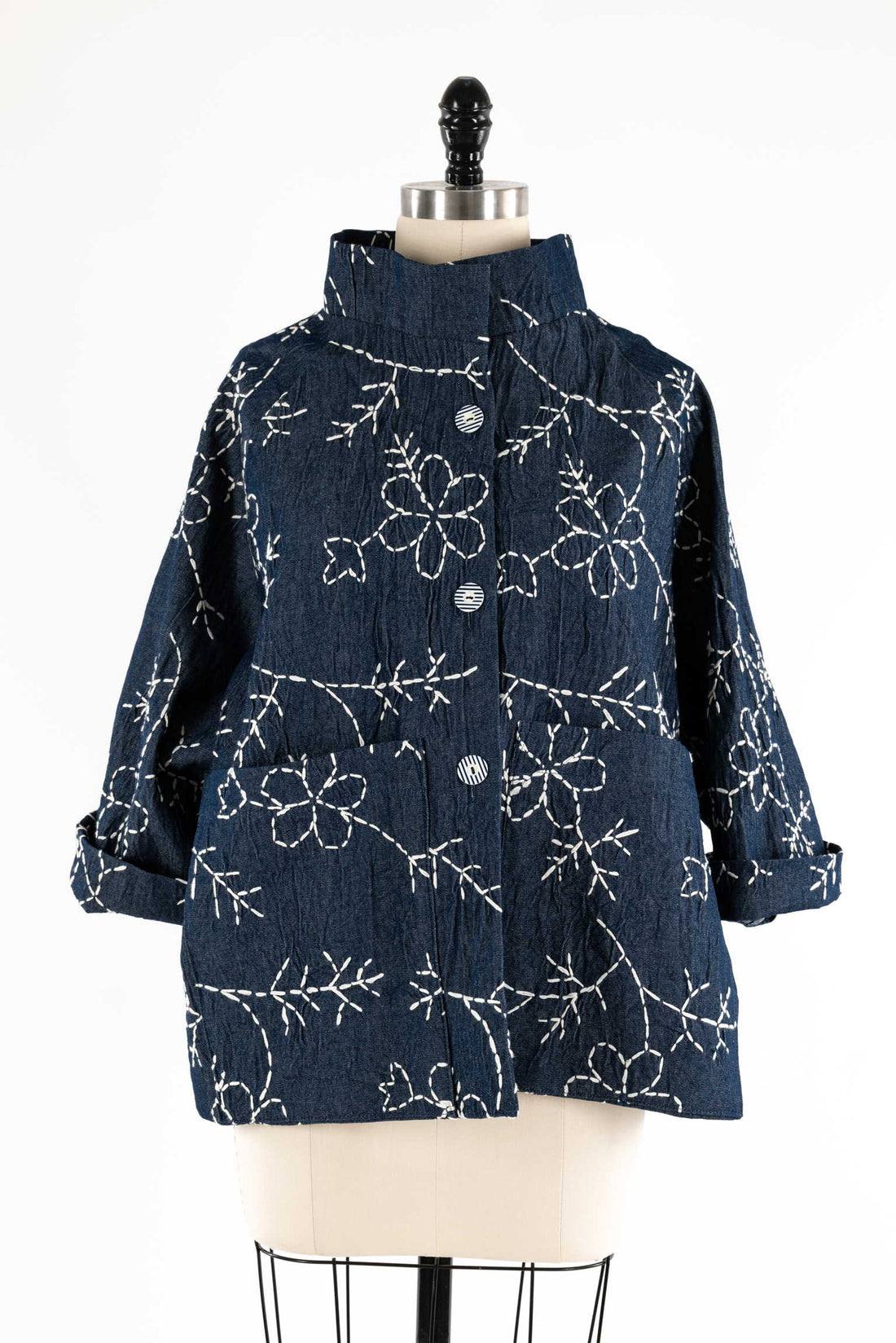 Denim jacket with white floral embroidery, button front, rolled sleeves, displayed on mannequin