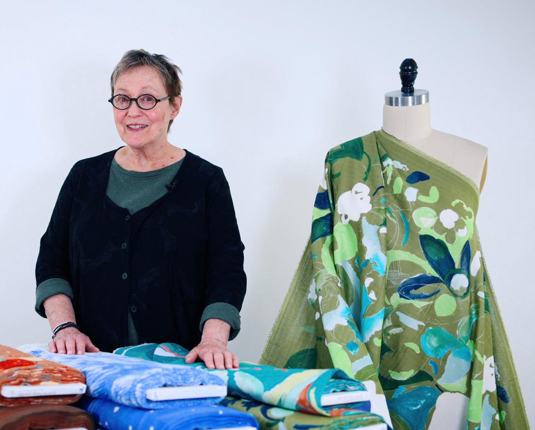 Woman with fabric bolts and floral print draped on mannequin, showcasing designer textiles for sewing