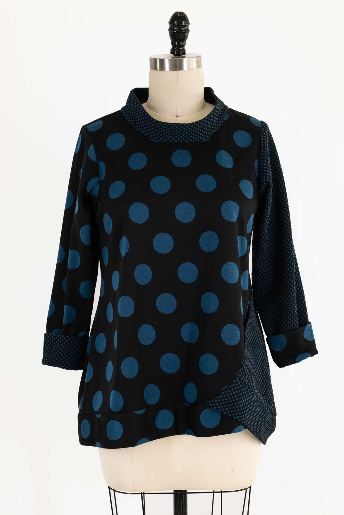 Black and blue polka dot knit top with 3/4 sleeves and asymmetrical hem
