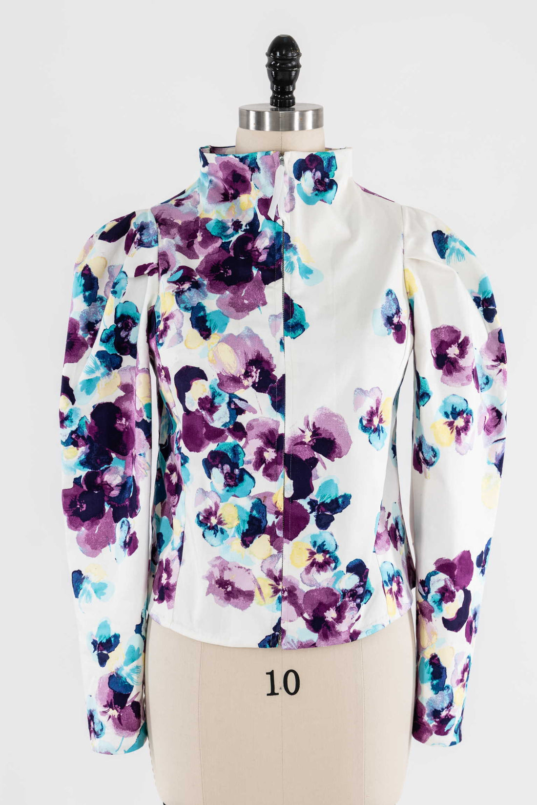 Floral print jacket with puff sleeves on mannequin, showcasing vibrant purple, blue, and yellow flowers on white fabric