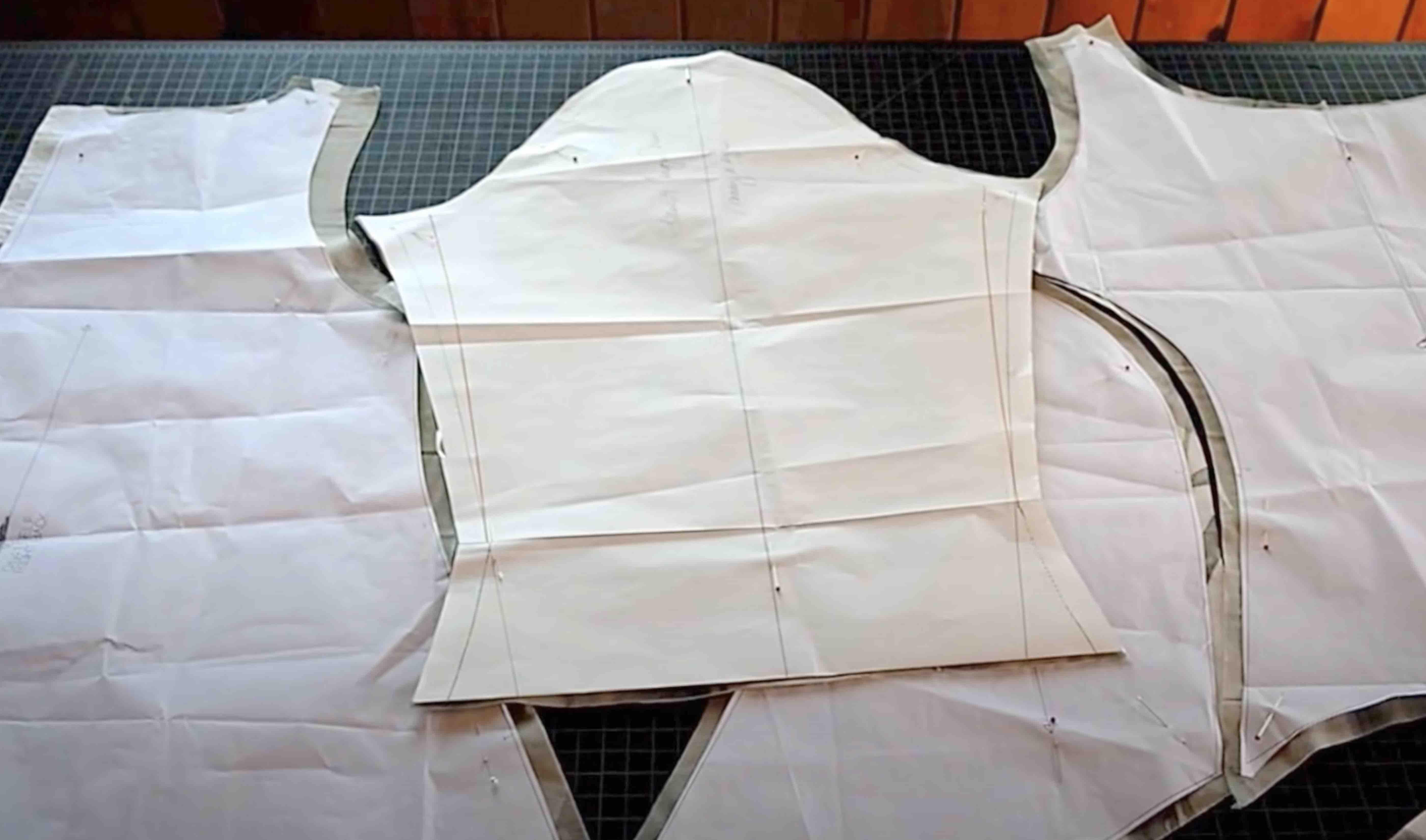 Fabric pattern pieces pinned on cutting mat for sewing project