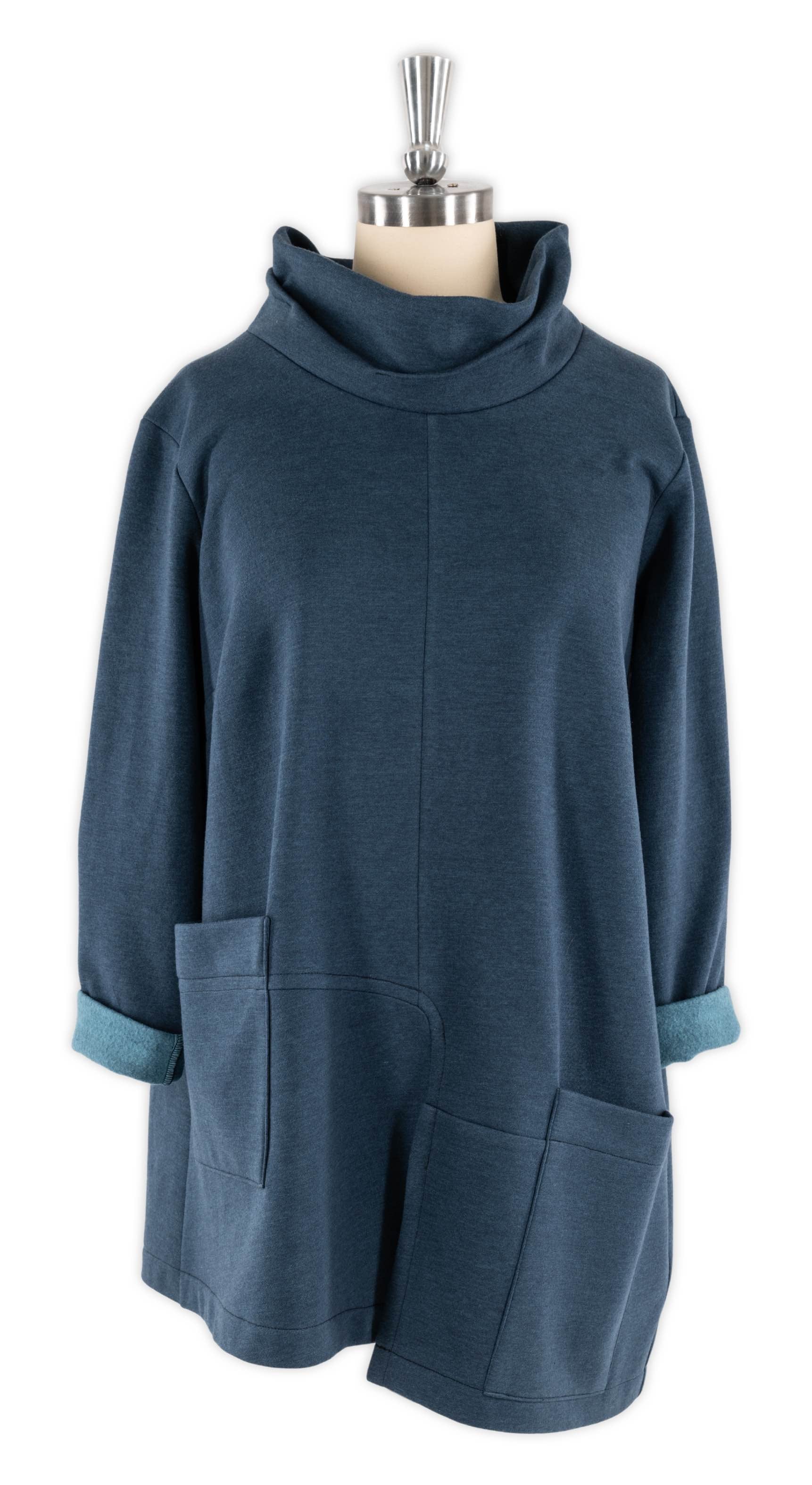 Blue knit tunic with cowl neck, rolled sleeves, and front pockets on mannequin