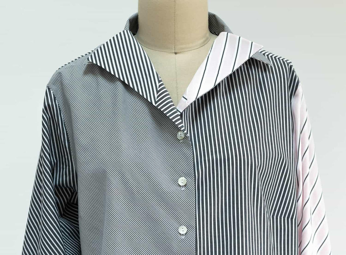 Black and white striped shirt with pink sleeve detail, button-front design on mannequin