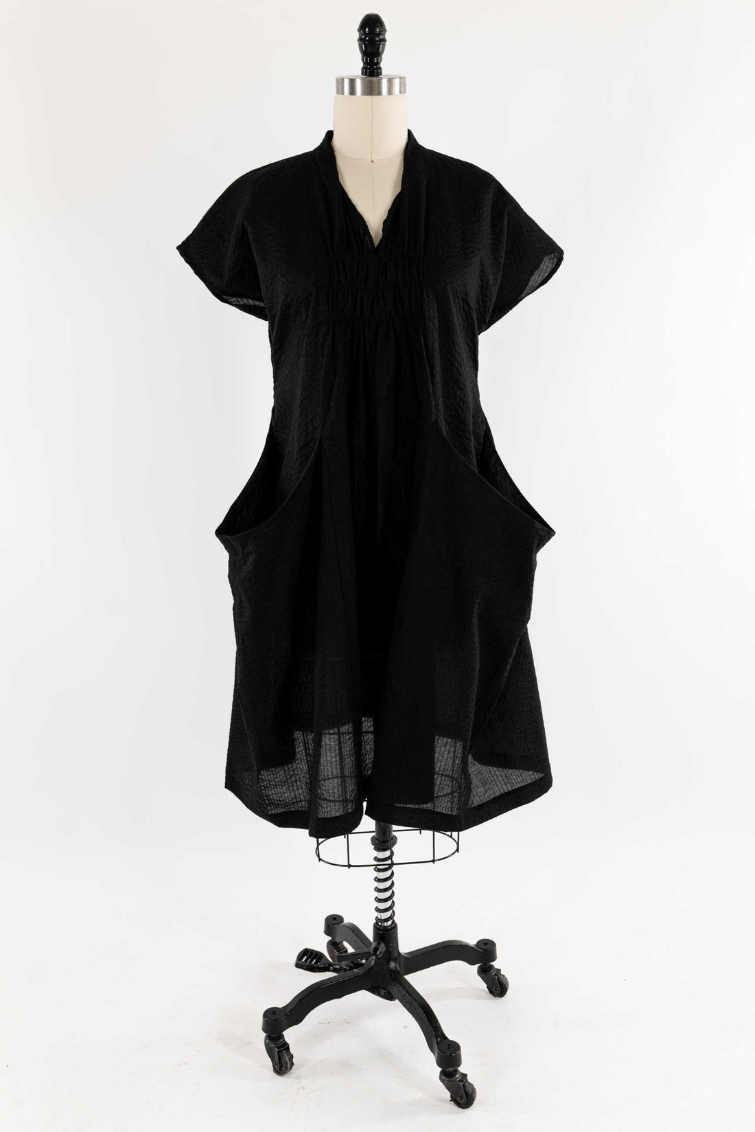 Black textured fabric dress with V-neck and short sleeves on mannequin, ideal for sewing projects