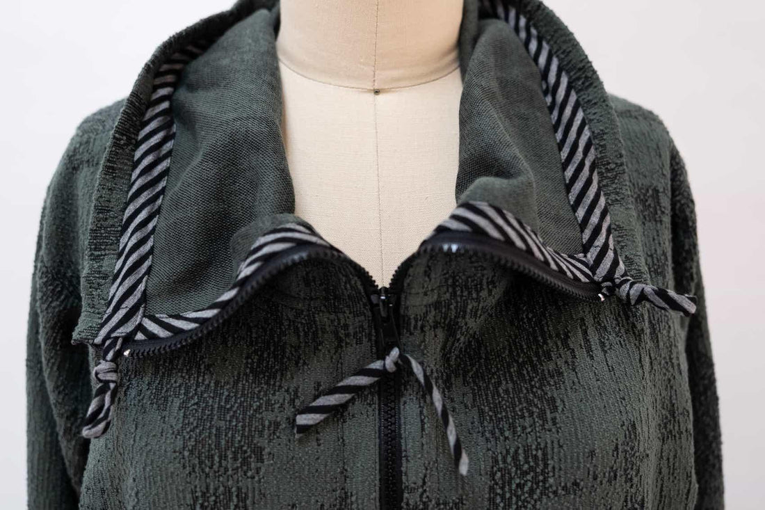 Dark green textured knit jacket with striped hood lining and zipper detail, ideal for sewing apparel projects.