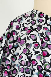 Floral print fabric with purple, pink, and green blooms on white background, ideal for apparel sewing